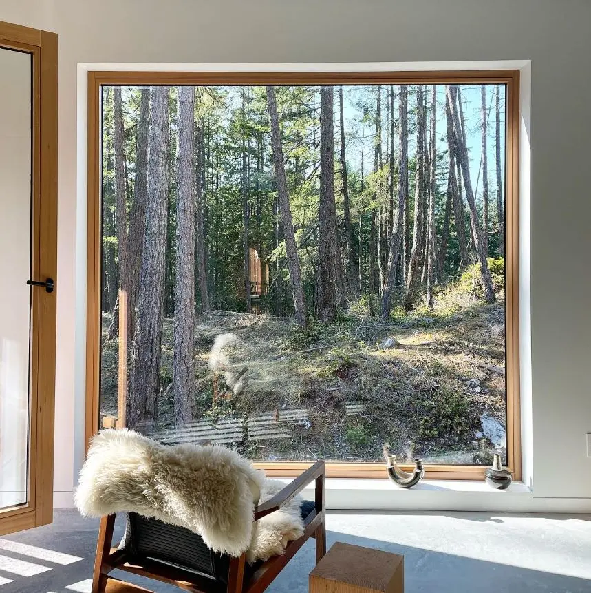 Large all-wood Fenstür picture window framing the forest from a finished Bowen Island room