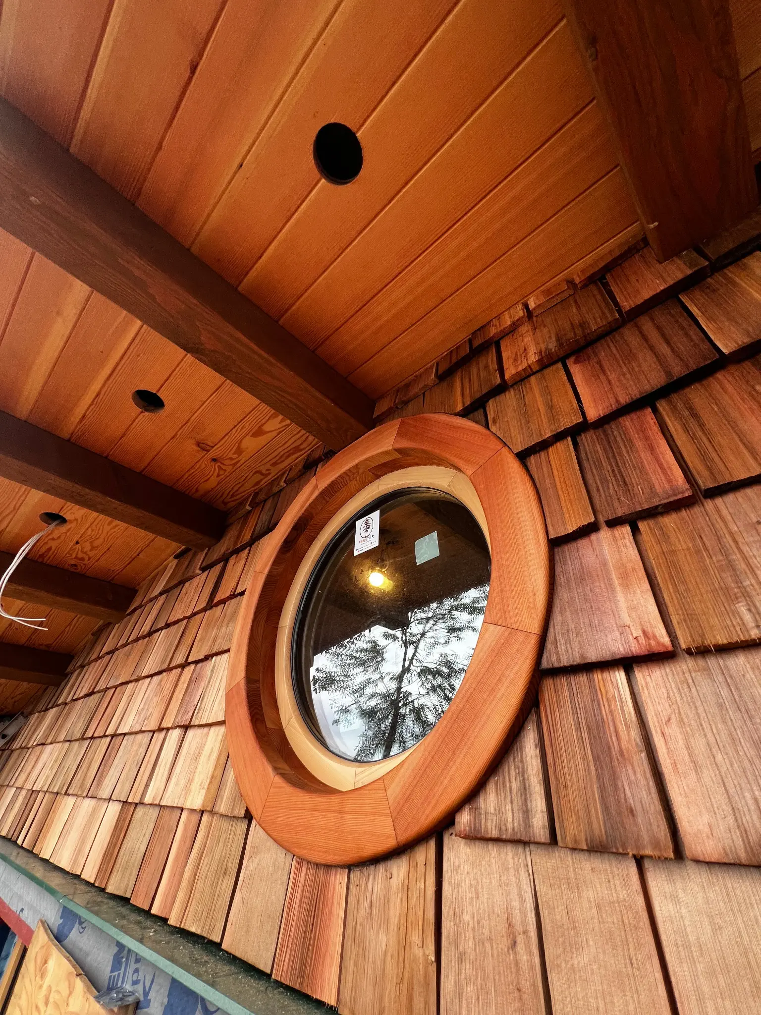 Custom round Fenstür window set into cedar shingles