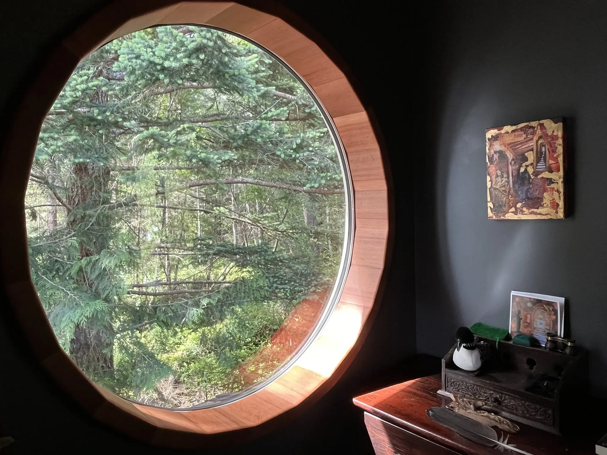 Custom round all-wood window framing the surrounding forest