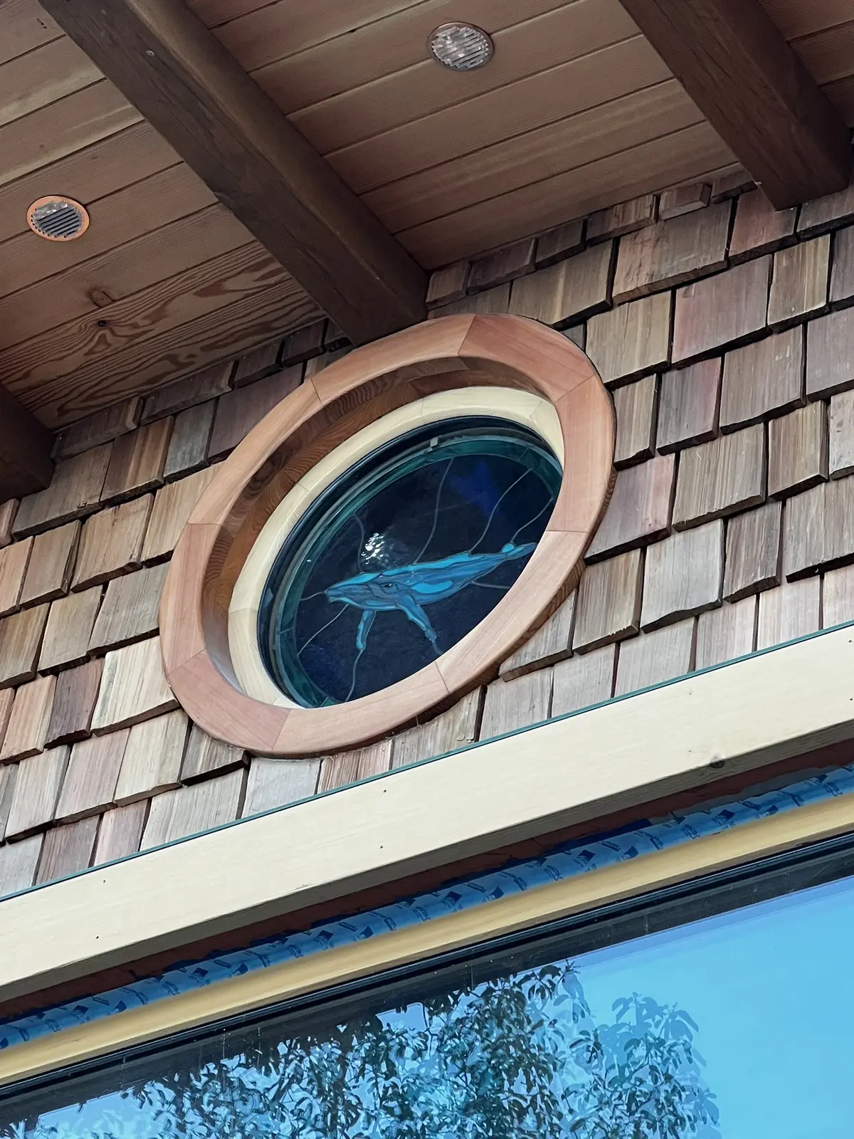 Custom round whale-glass window in its sculpted wood frame