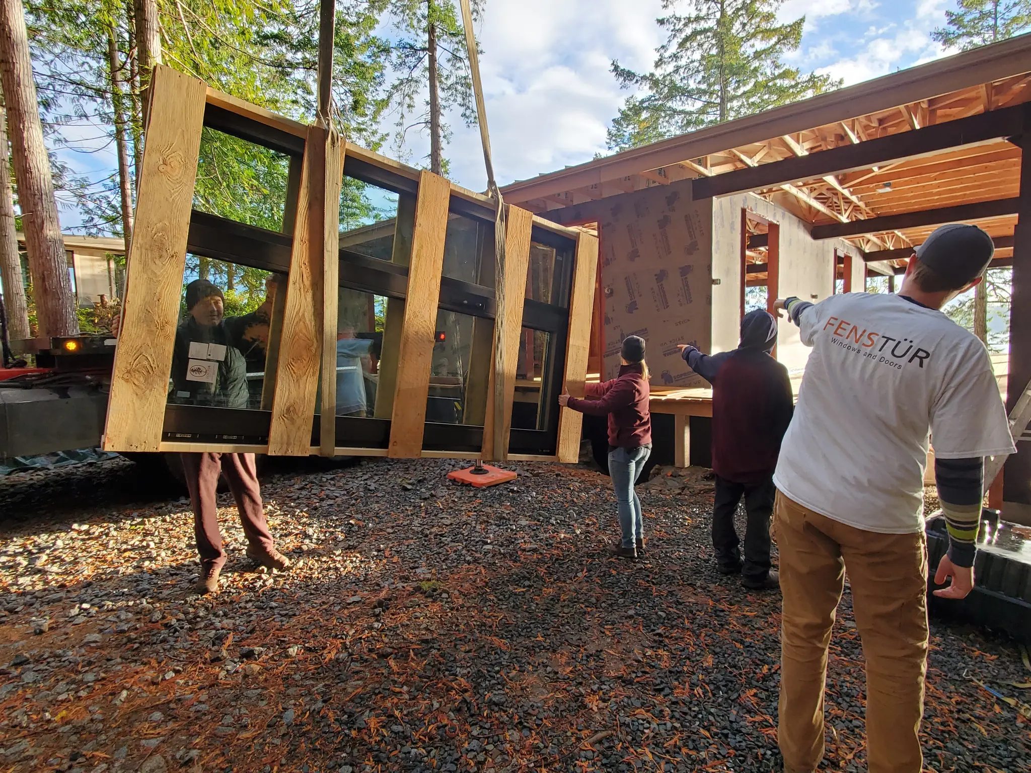 Fenstür crew guiding a large glazed assembly into the seaside home