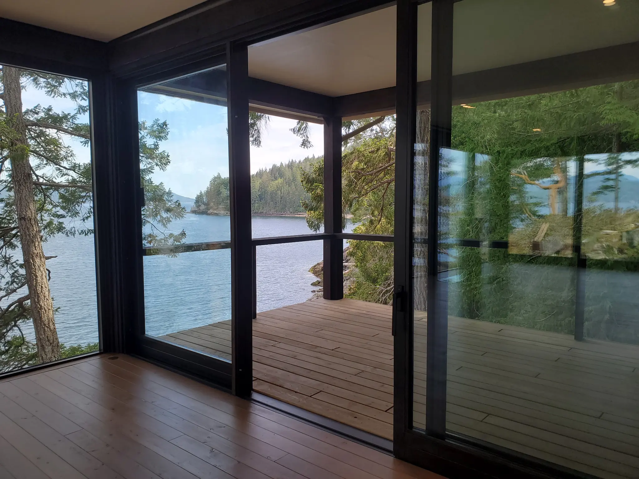 Open lift-and-slide doorway framing the forest and shoreline