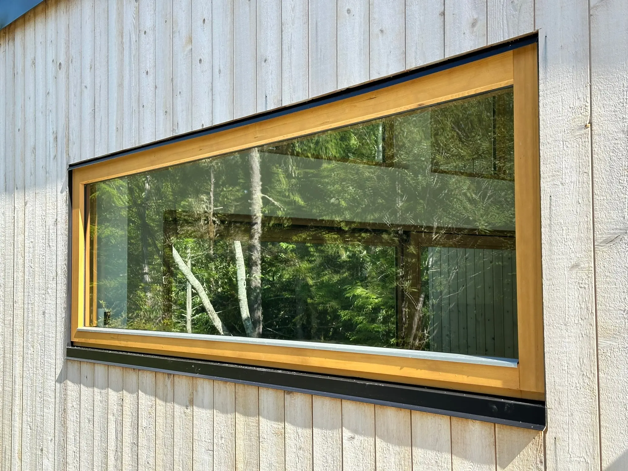 Large all-wood picture window set into coastal cedar siding